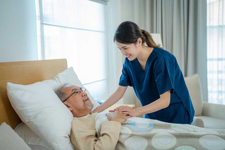 A caregiver talks with a senior resident in a comfortable assisted living common room.