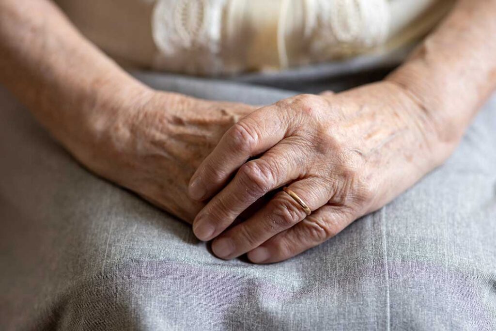 Older resident choosing clothing with a caregiver in a bright, private assisted living room.